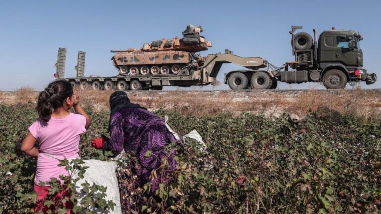 Agricultural workers watch Turkish military vehicles heading to northern Syria - October 12, 2019 (EPA/Sedat Suna)