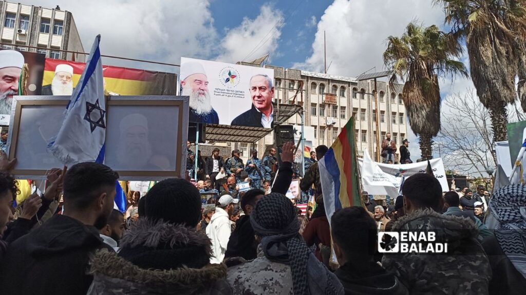 Protesters raise photos of Israeli Prime Minister Benjamin Netanyahu and Sheikh Hikmat al-Hijri during protests in Suwayda, April 11, 2026. (Enab Baladi)