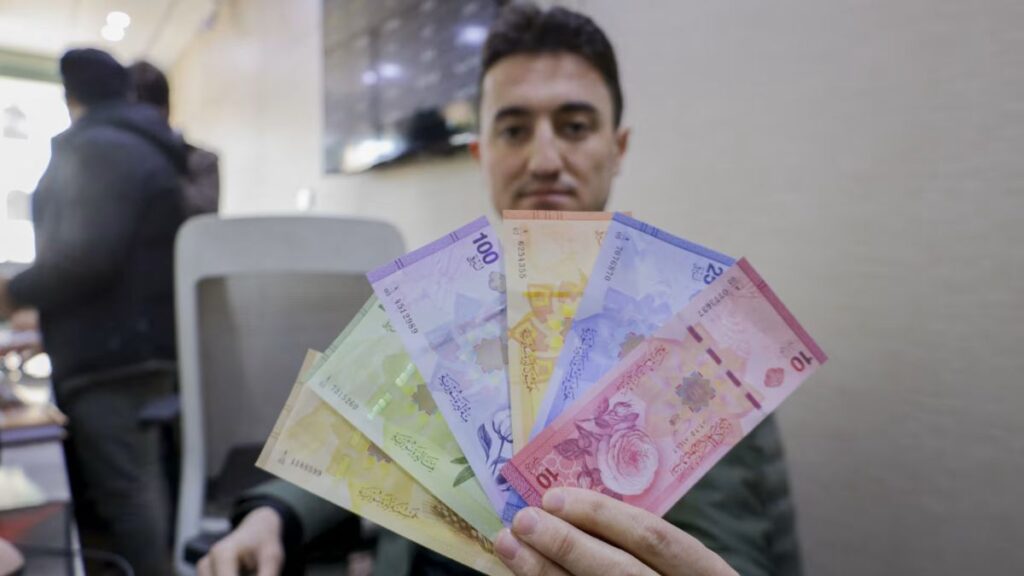 An employee at a financial institution in Damascus displays banknotes from the new Syrian pound denominations, 31 May 2026 (AFP)
